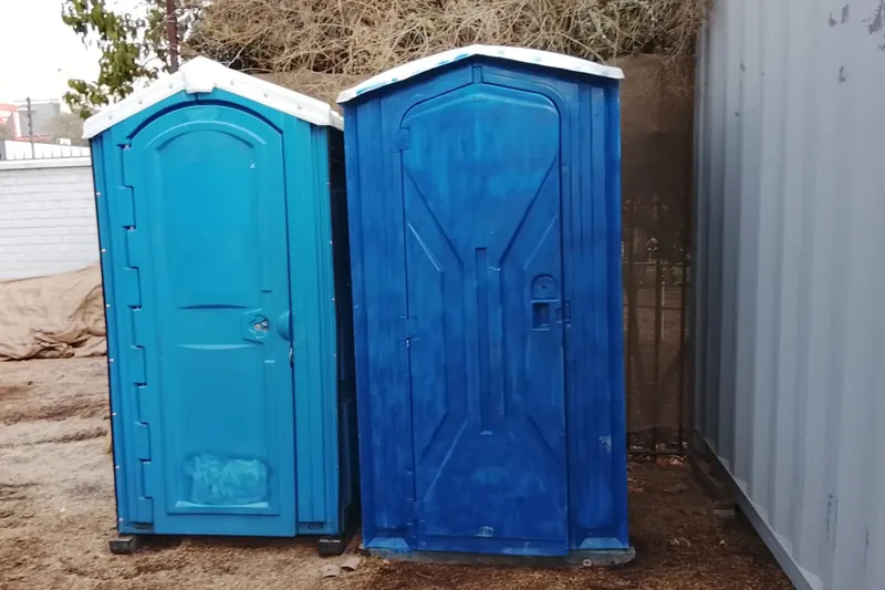 Dos baños químicos azules instalados en terreno, listos para el servicio